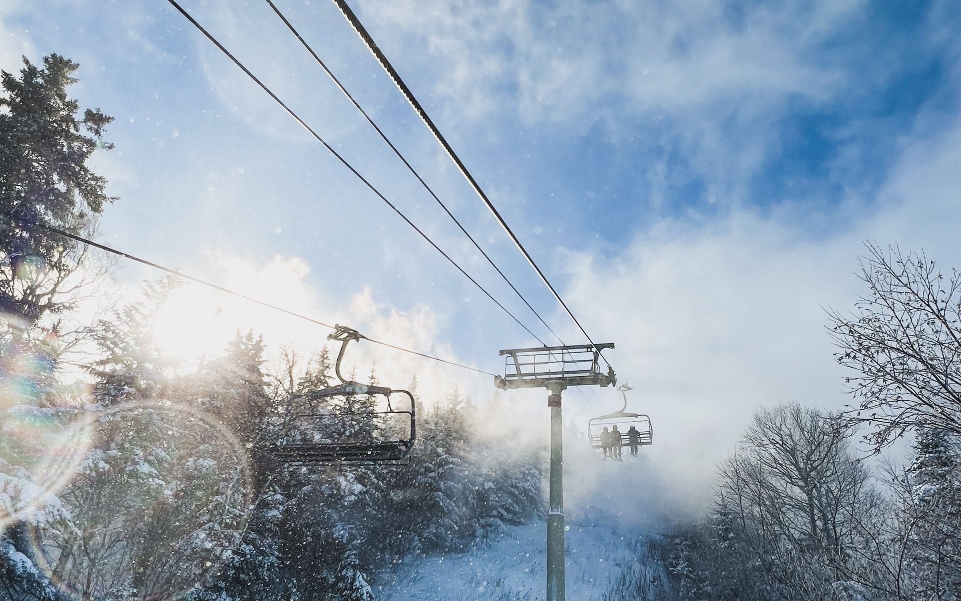 Skiers on a groomed blue trail at a Vermont mountain resort on a clear winter morning with snow-covered pines