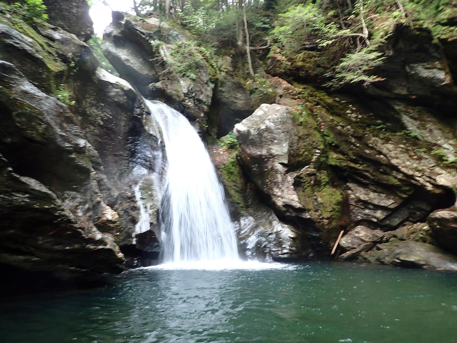 Bingham Falls waterfall in Stowe, Vermont, dropping into a green pool between moss-covered granite boulders