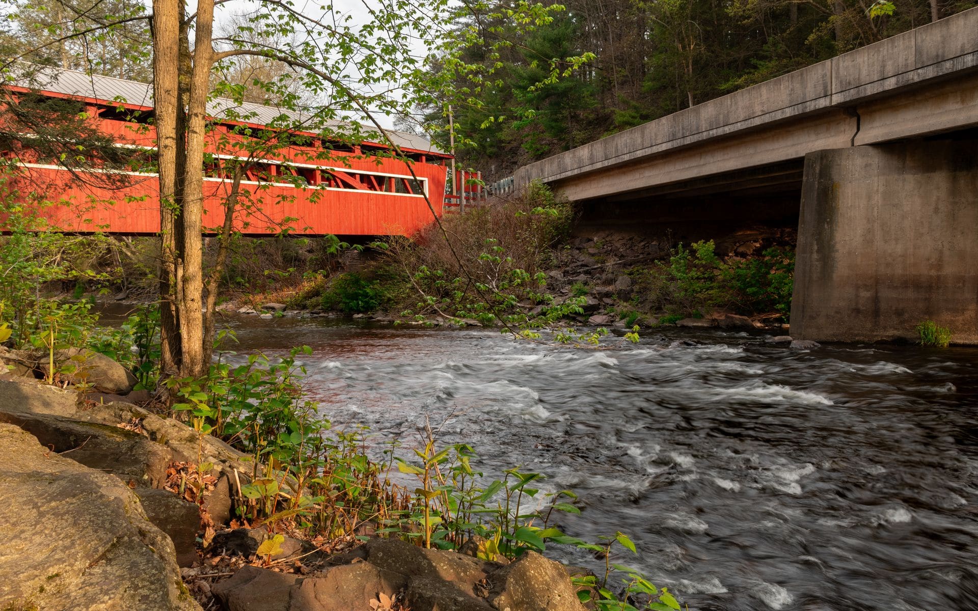 The red Taftsville Covered Bridge spanning the Ottauquechee River near Woodstock, Vermont on a clear October day