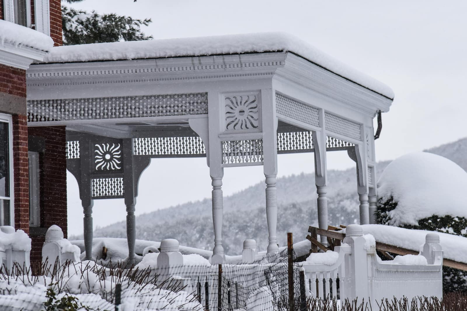 Snow-covered ornate Victorian porch of the Marsh-Billings-Rockefeller mansion in Woodstock, Vermont, with snow-laden Green Mountains in the background